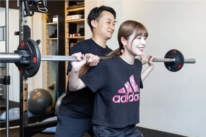 ダンベルでトレーニングをする女性とトレーナーの写真