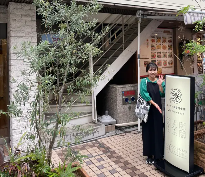 「グレフル鍼灸接骨院」の看板の前でポーズをとる女性の写真