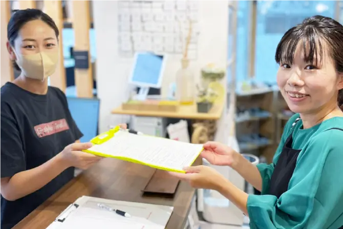 受付でアンケート用紙を受け取る女性の写真