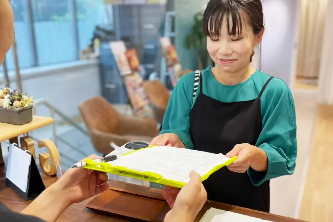 記入したアンケートを受付に渡す女性の写真